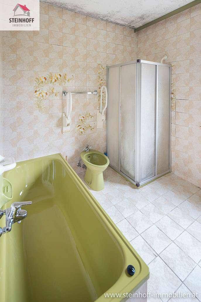 Badezimmer im Stil der 80er Jahre mit grüner Badewanne, Bidet und Duschkabine.
