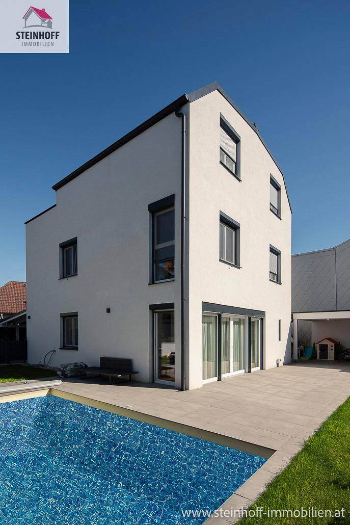 Ansicht des modernen Hauses mit klaren Linien, erfrischendem Pool und sonniger Terrasse für Outdoor-Aktivitäten.