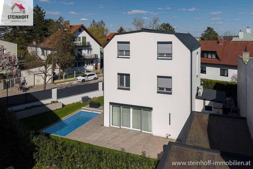 Ansicht des modernen Hauses mit Pool, Terrasse und Rollläden an den Fenstern in sonniger Umgebung.