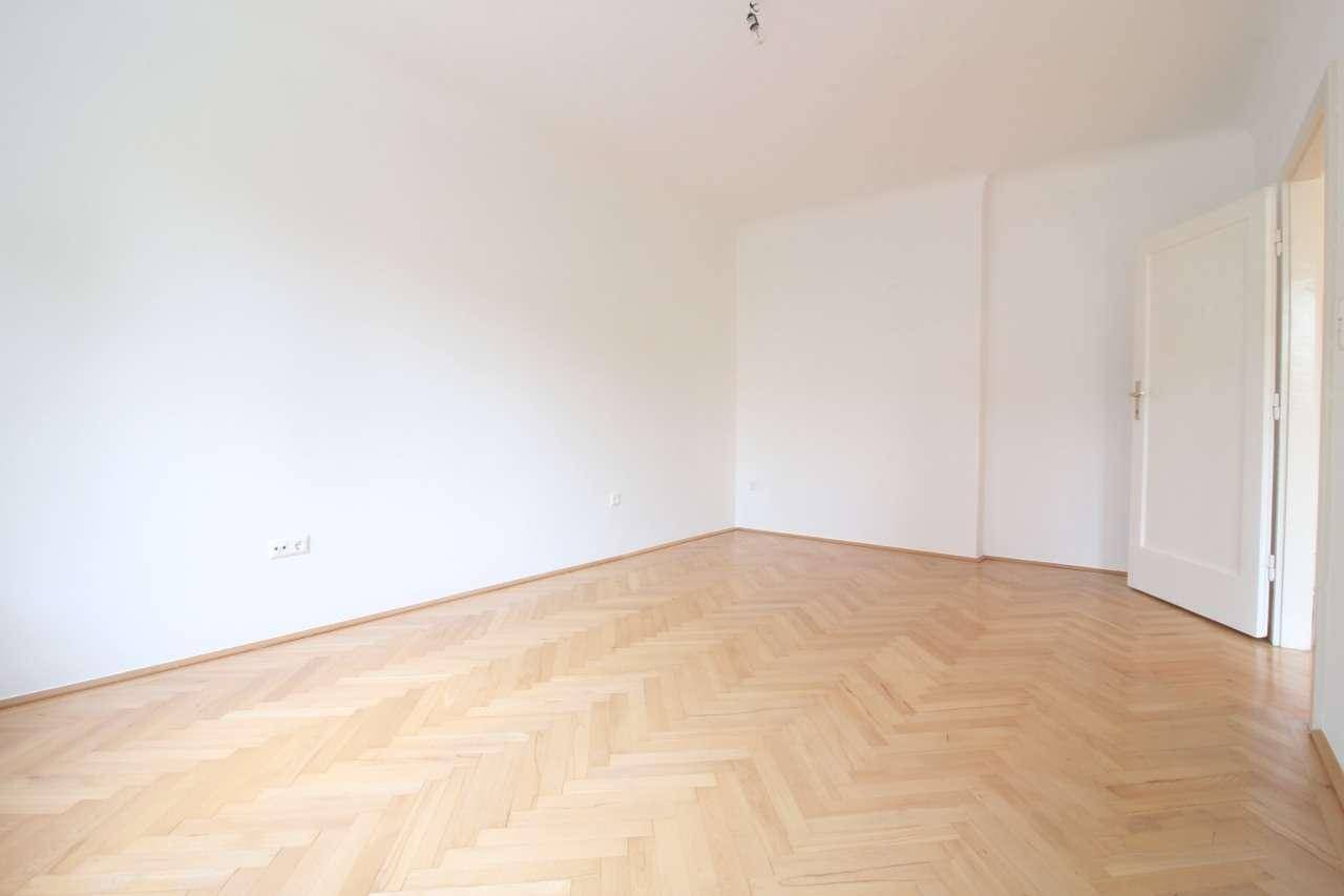 Leerer Raum mit hellem Fischgrätparkett und weißen Wänden, bereit zur individuellen Gestaltung.
