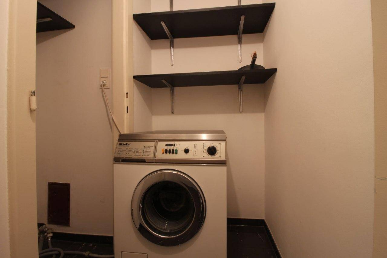 Hauswirtschaftsraum mit Waschmaschine der Marke Miele und praktischen Wandregalen.