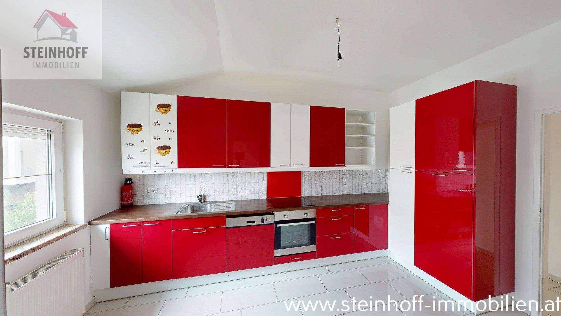 Moderne Küche mit roten und weißen Hochglanzschränken, integriertem Backofen und Fliesenboden.