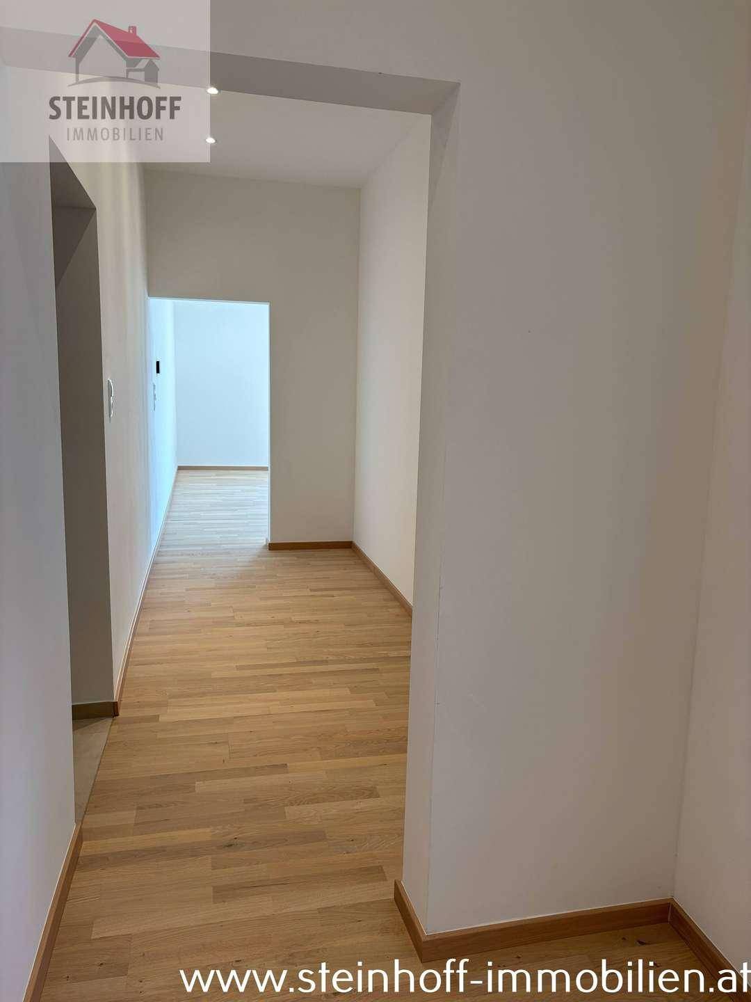 Langer, heller Flur mit Parkettboden, der zu weiteren Räumen der Wohnung führt.