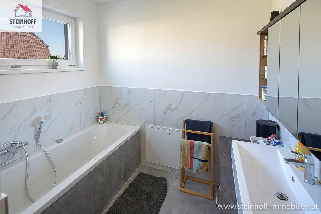 Badezimmer mit Badewanne, Einzelwaschbecken und Spiegelschrank, hell und funktional gestaltet.