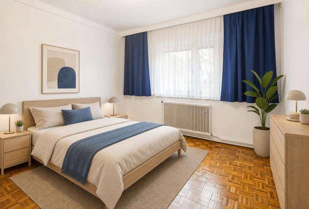 Gemütliches Schlafzimmer mit Holzbett, Parkettboden, blauen Vorhängen und einem Heizkörper unter dem Fenster.