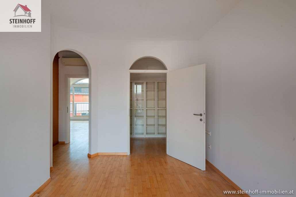 Heller Flur mit Holzboden und eleganten Rundbögen, der zu weiteren Räumen führt.