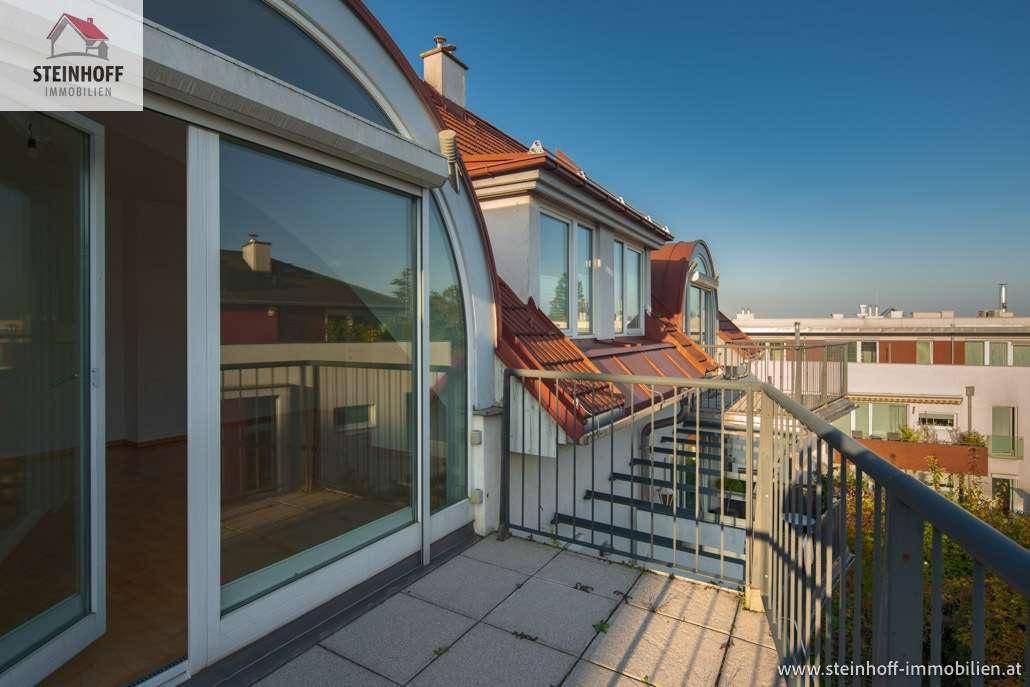 Geräumiger Balkon mit Fliesenboden und Metallgeländer, bietet Blick auf die umliegenden Dächer.