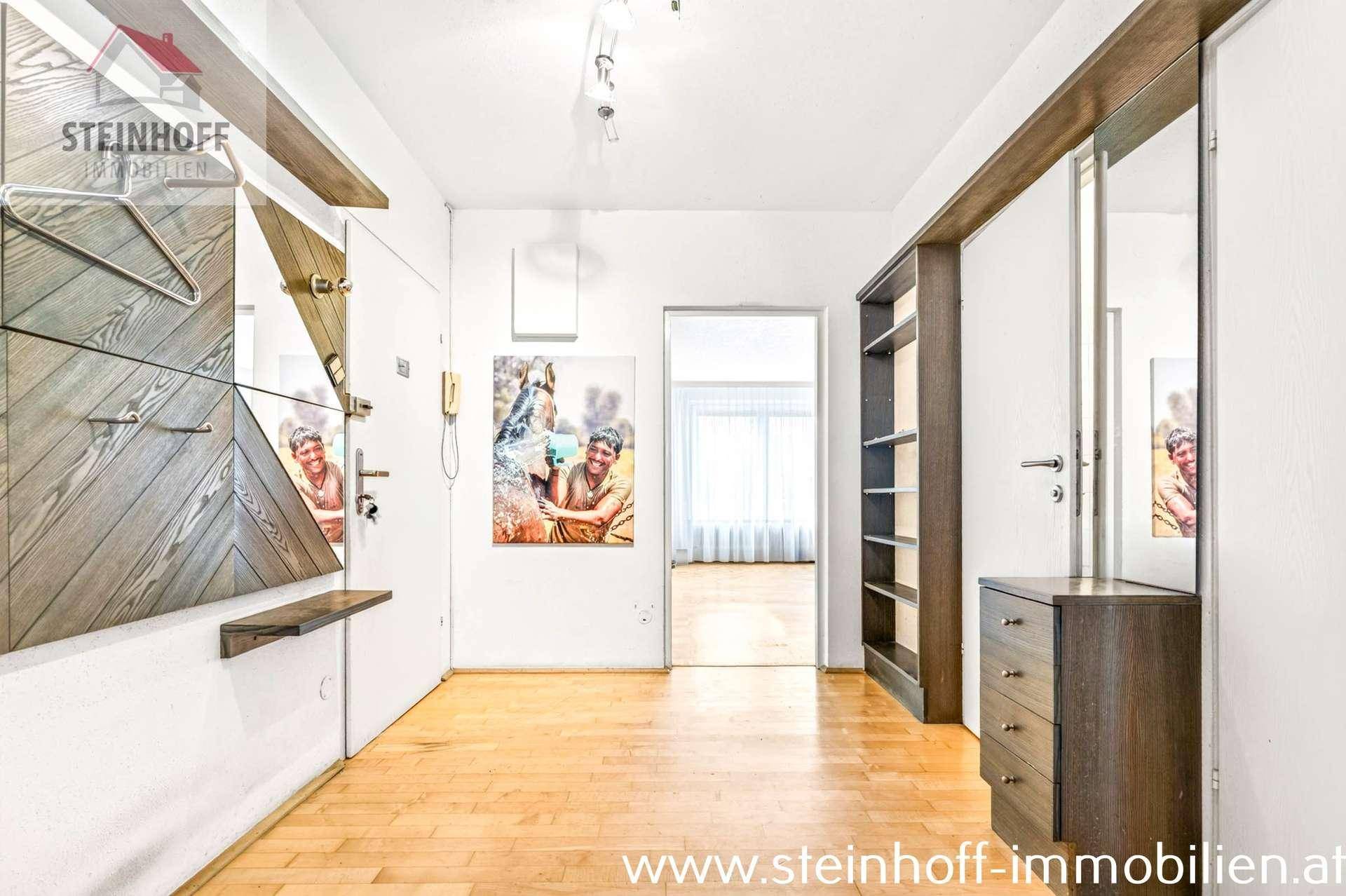 Heller Flur mit Holzparkett, Garderobe und Bücherregal, der den Zugang zu den Zimmern ermöglicht.