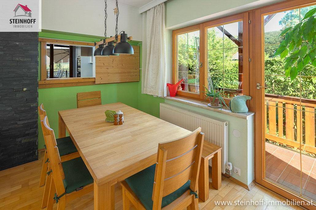 Essbereich mit Holztisch, Stühlen und Zugang zu einem Balkon oder einer Terrasse.