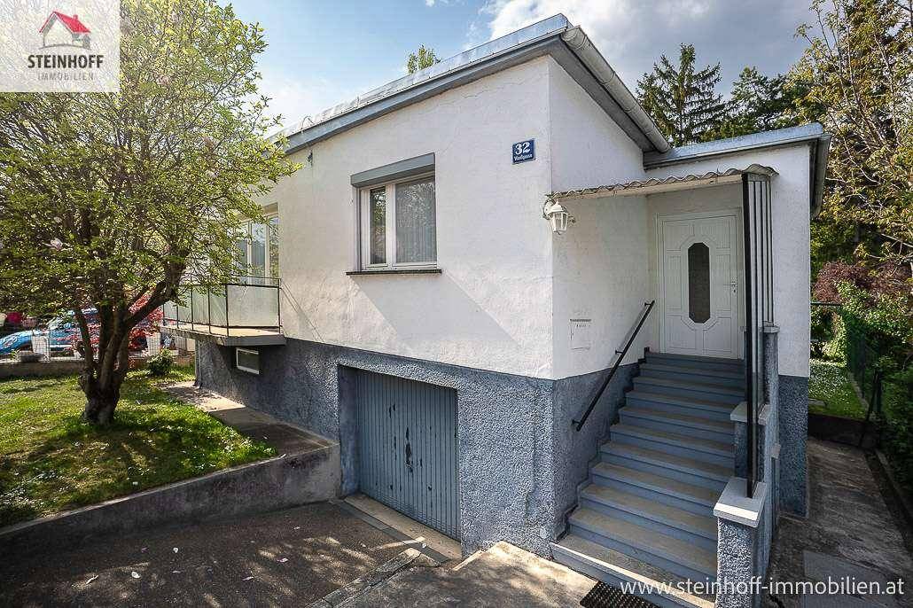 Haupteingang des Hauses mit Treppe und integrierter Garage im Untergeschoss.