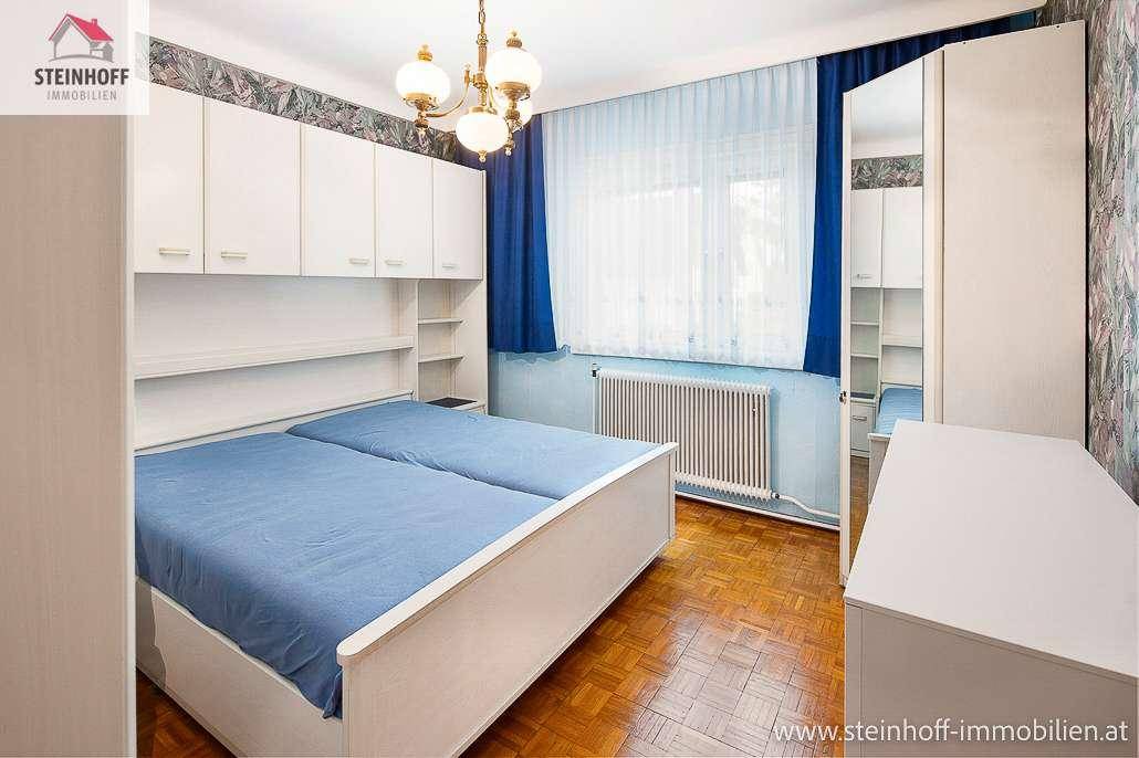 Schlafzimmer mit zwei Einzelbetten, weißen Einbauschränken und Parkettboden.