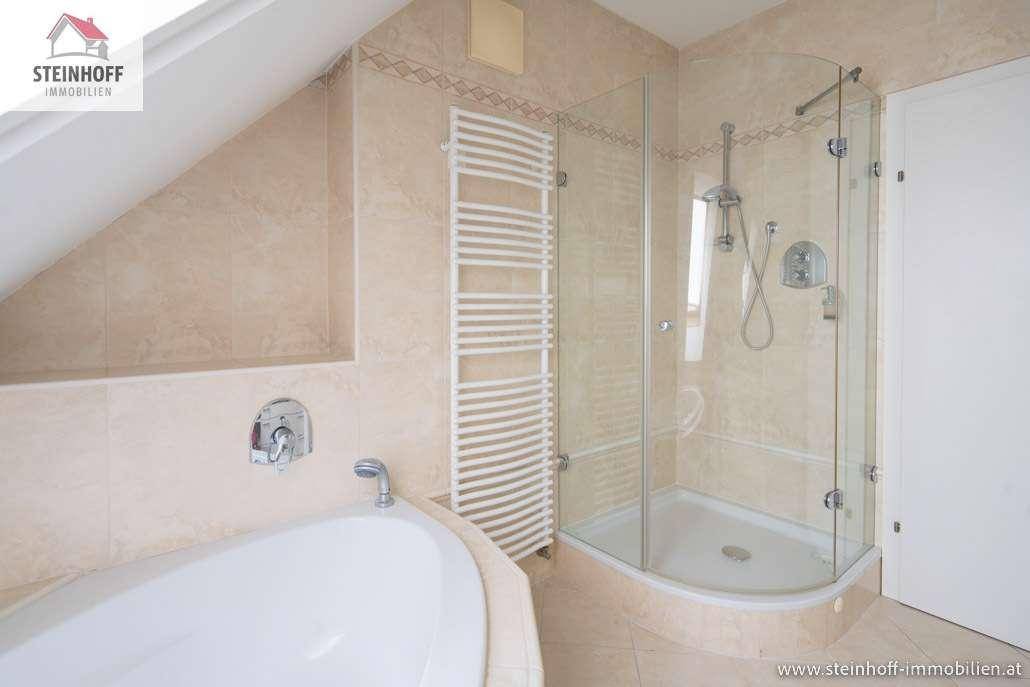 Badezimmer mit Eckbadewanne, Duschkabine und beheiztem Handtuchhalter unter einer Dachschräge.