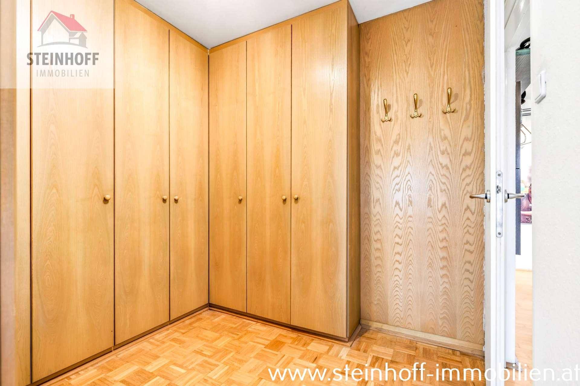 Geräumiger Bereich mit integrierten Holzschränken und Parkettboden, ideal als Ankleidezimmer.