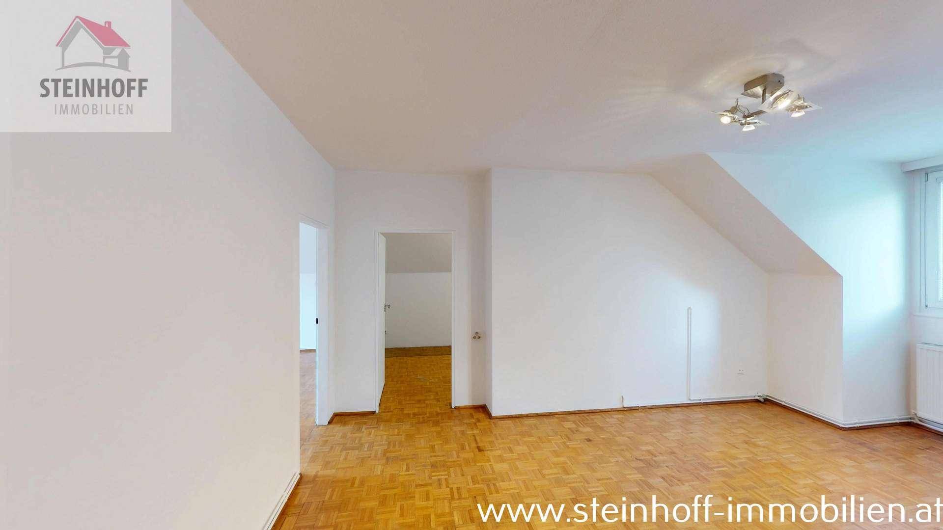 Geräumiges Wohnzimmer mit Parkettboden, Dachschrägen und viel Tageslicht.