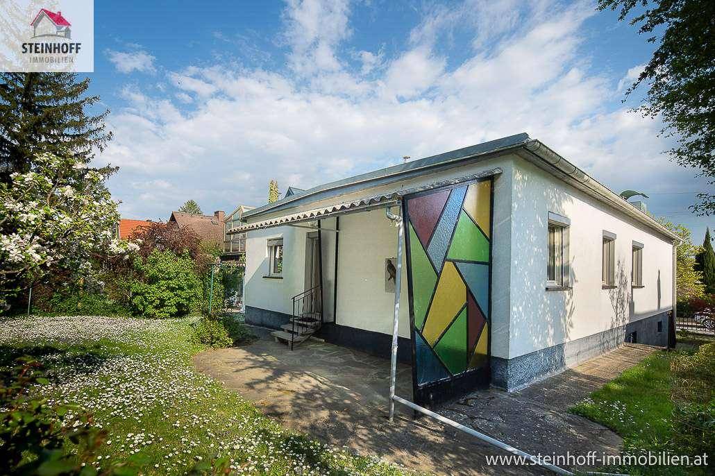 Rückseite des Hauses mit farbenfroher Glastür und Zugang zum blühenden Gartenbereich.