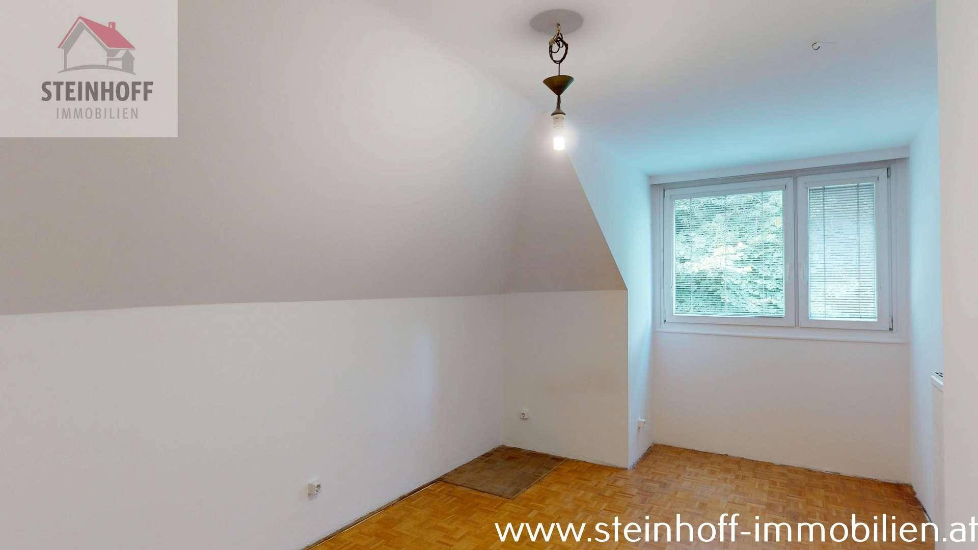 Heller Raum mit Parkettboden, Fenster und charakteristischen Dachschrägen.