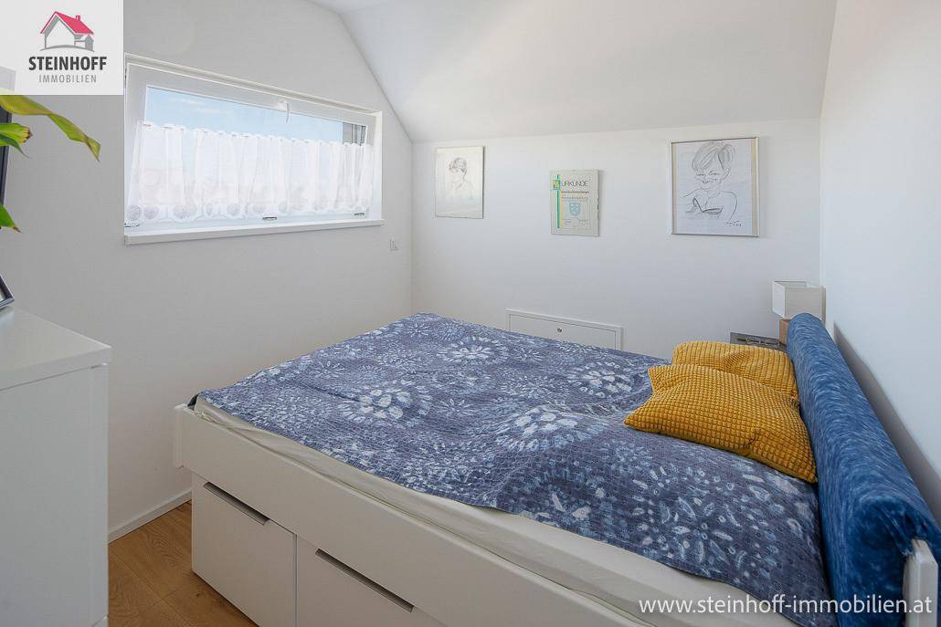 Gemütliches Schlafzimmer im Dachgeschoss mit Bett und Fenster unter einer einladenden Dachschräge.