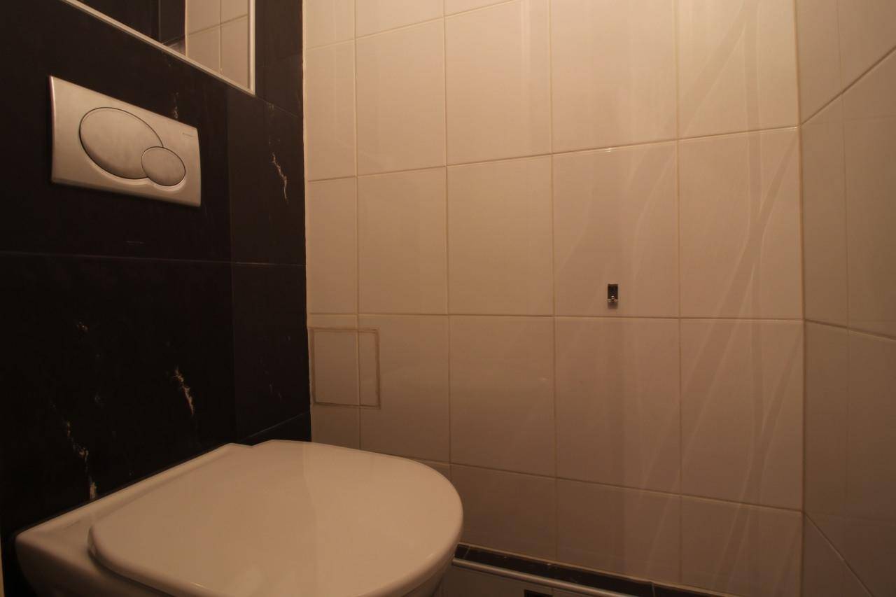 Separate Toilette mit weißen und schwarzen Fliesen und wandmontiertem Spülkasten.