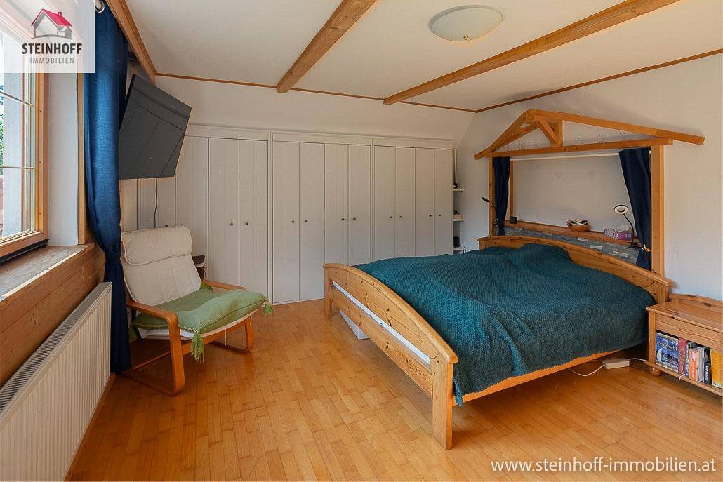 Schlafzimmer mit Holzboden, Einbauschränken und Holzbalken an der Decke.