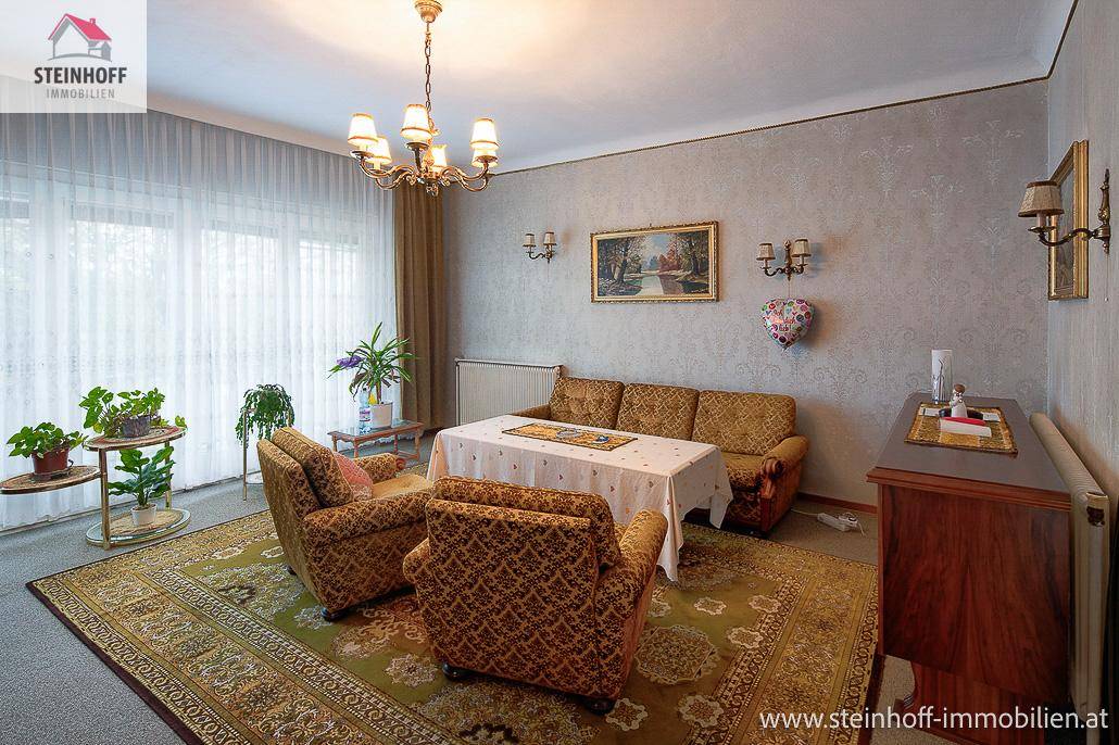 Geräumiges Wohnzimmer mit bequemen Sofas, Teppich und einem großen Fenster.