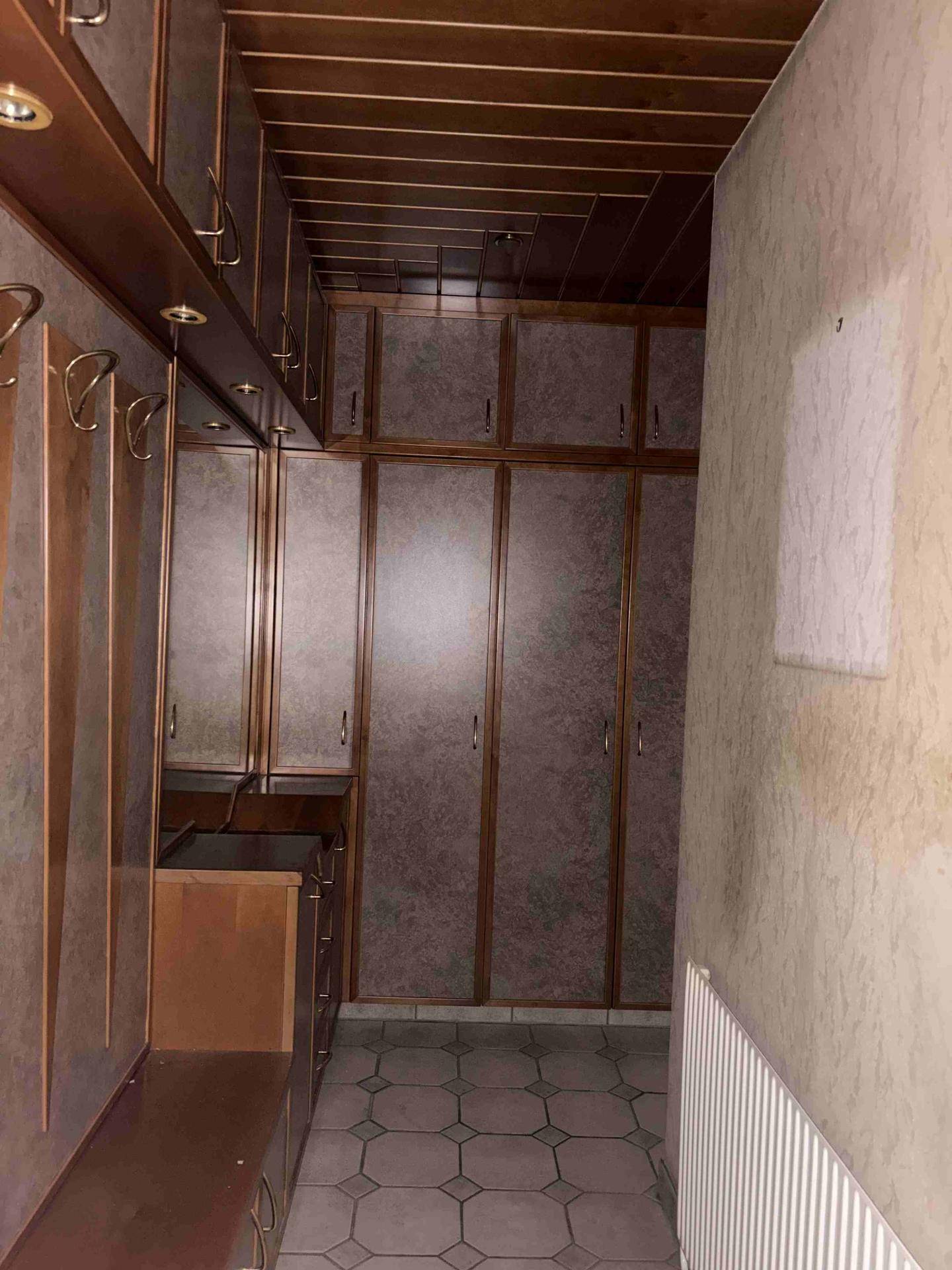 Flur mit Einbauschränken, Holzdecke und Fliesenboden, der viel Stauraum bietet.