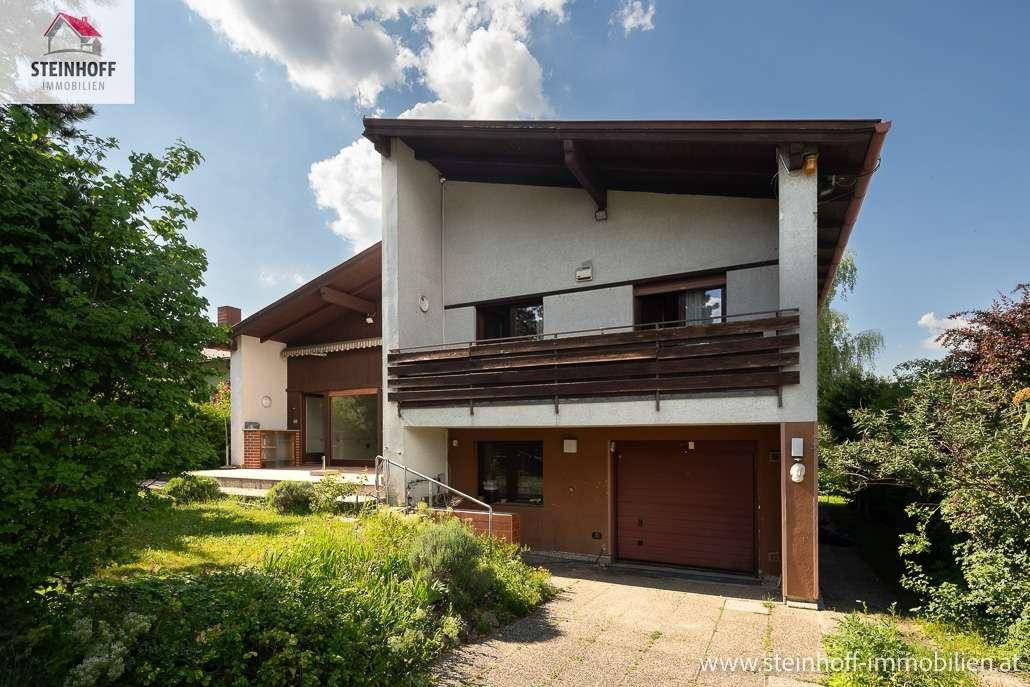 Vorderansicht des Hauses mit Garage und Gartenbereich unter blauem Himmel.
