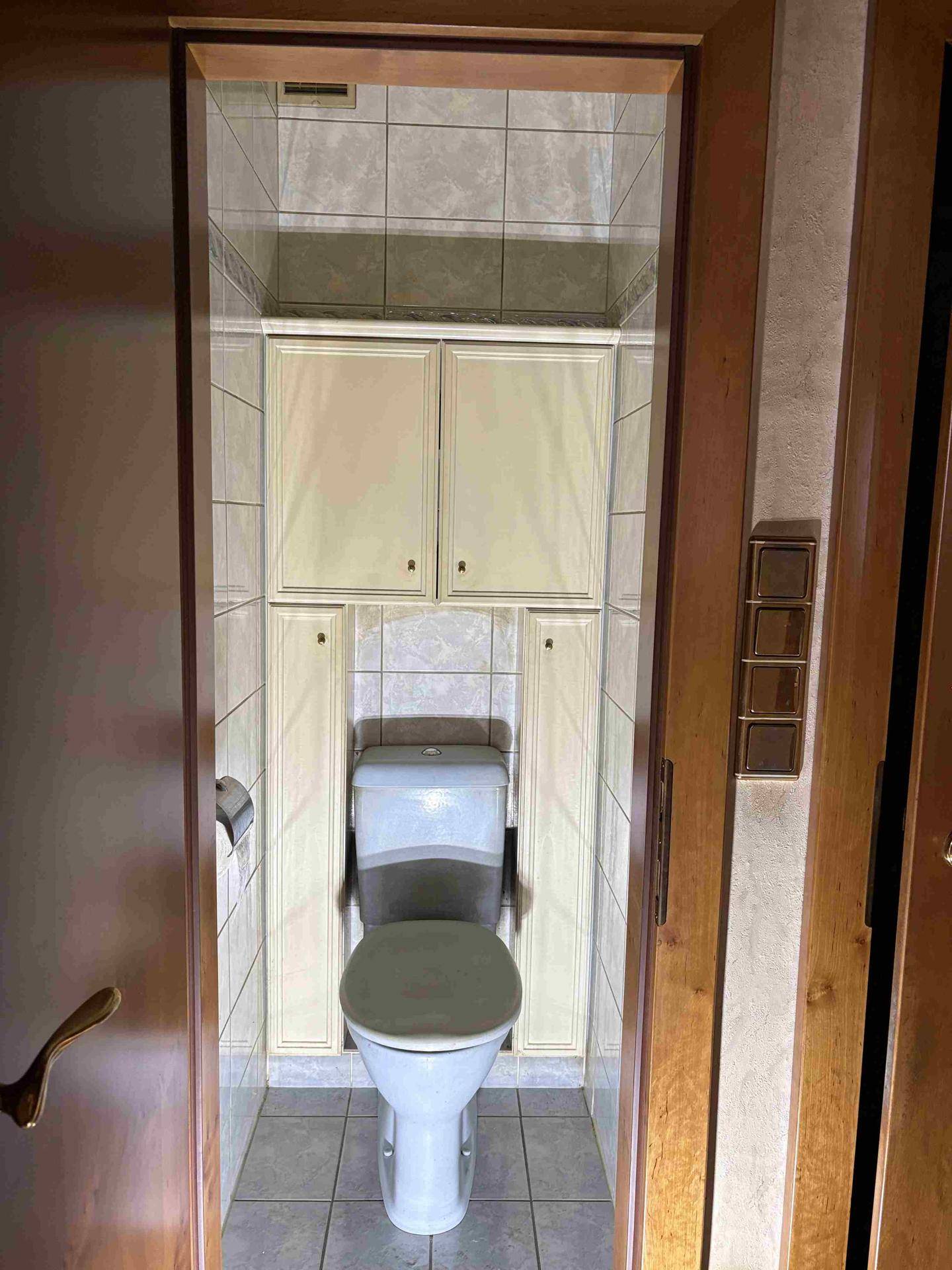 Kleines WC mit Wand-WC und Fliesen an Wänden und Boden, funktional und kompakt.