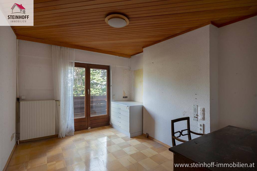Schlafzimmer mit Parkettboden, Holzdecke und direktem Zugang zu einem kleinen Balkon.