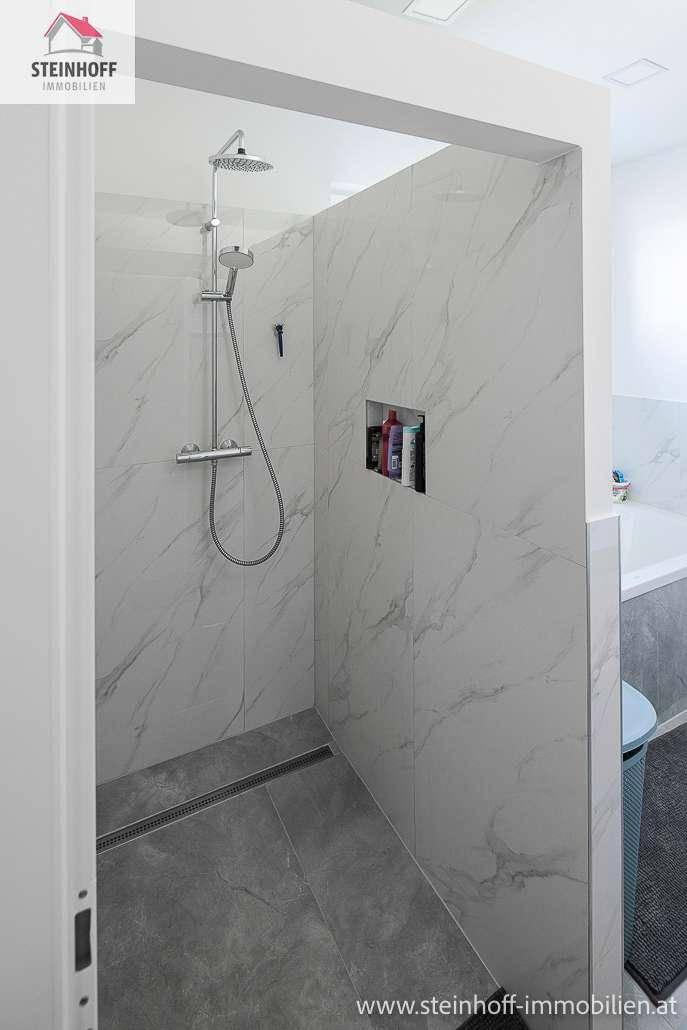 Modernes Badezimmer mit begehbarer Dusche, Regenduschkopf und eleganten Marmorfliesen.
