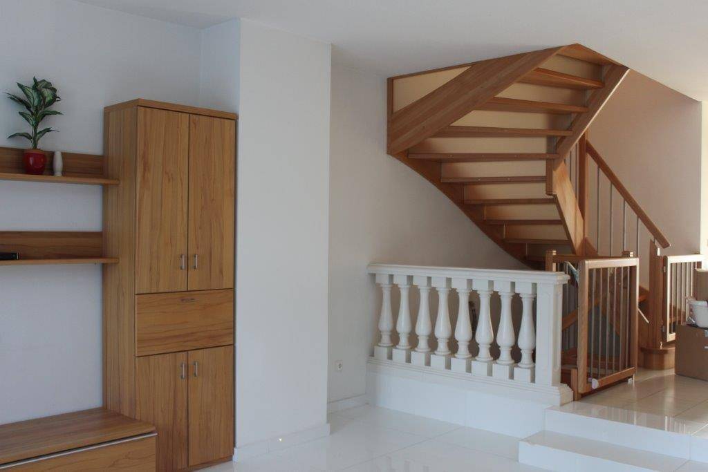 Wohnbereich mit Holzschrank und offener Holztreppe, die zum oberen Stockwerk führt.