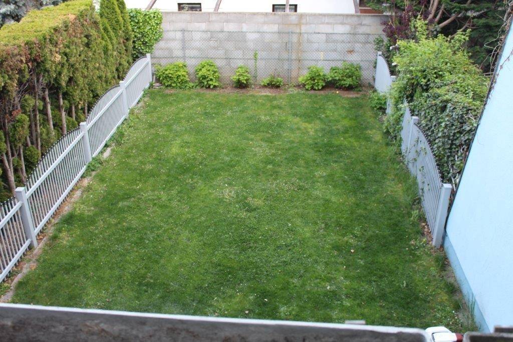 Gepflegter Garten mit Rasenfläche, umgeben von einem Zaun und Hecken.