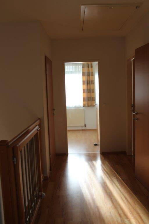 Heller Flur im Obergeschoss mit Holzfußboden und Blick in ein weiteres Zimmer.