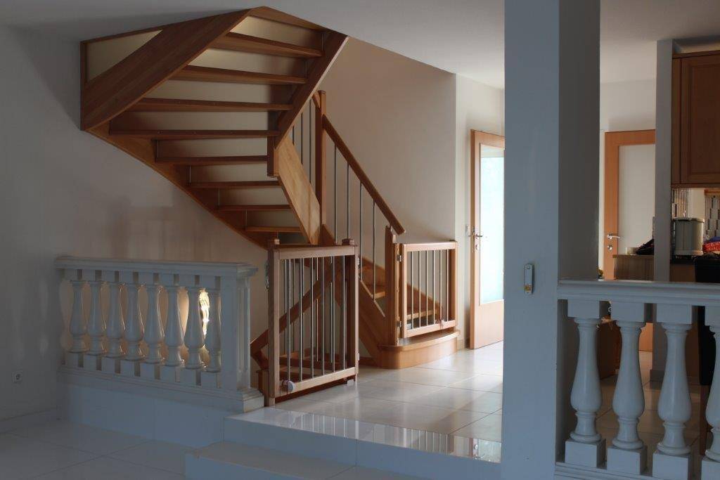 Offener Treppenbereich mit Holzstufen, Metallgeländer und einem weißen Balustraden-Element.