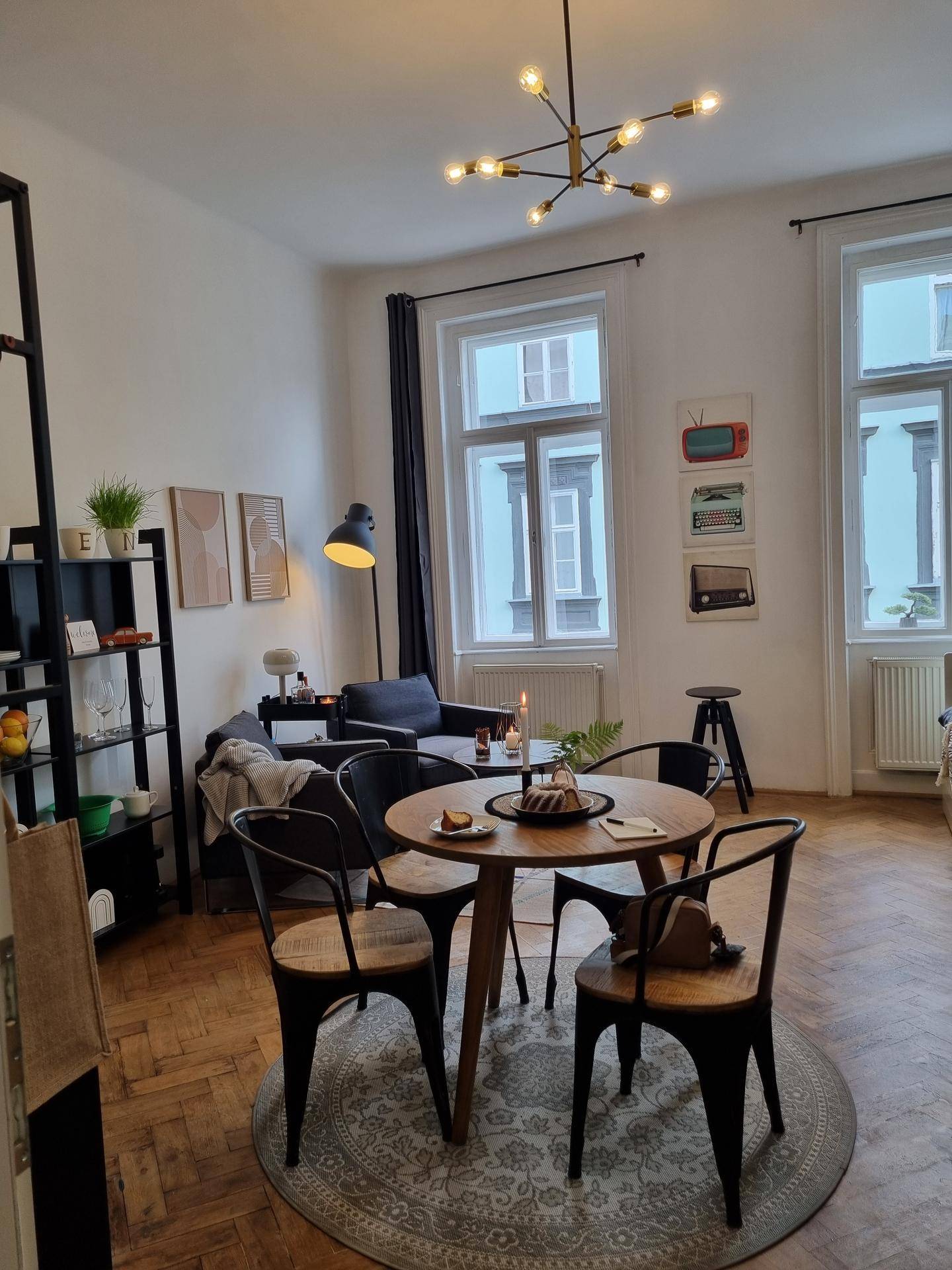 Heller Wohn- und Essbereich mit Esstisch, Sofa und großen Fenstern, die viel Licht hereinlassen.