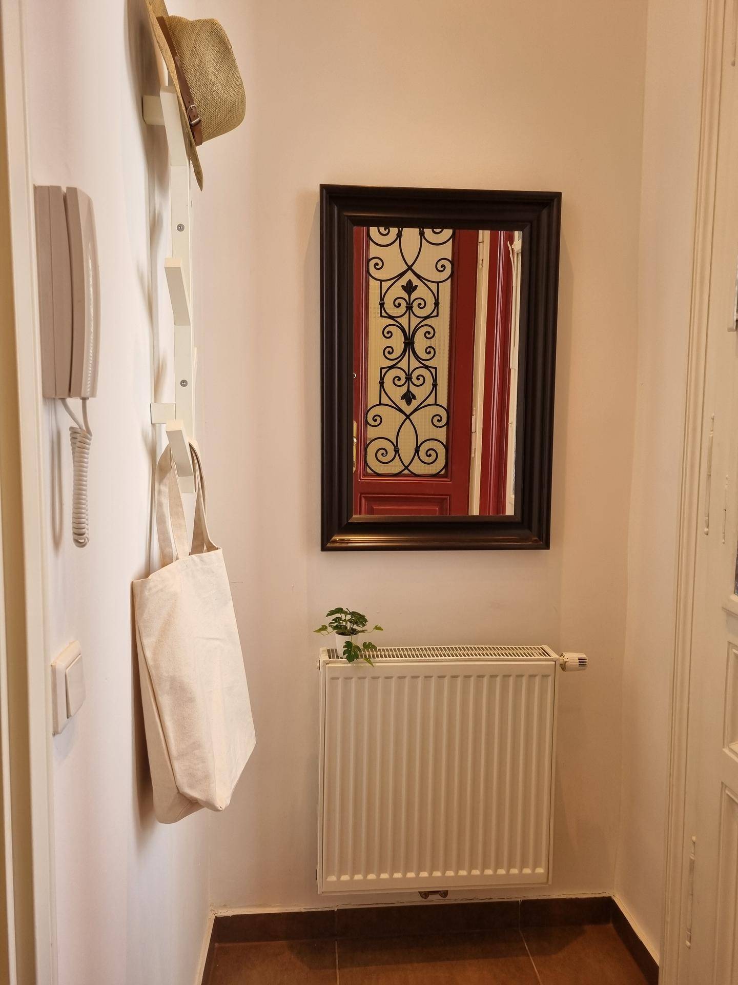 Heller Flur mit Spiegel, Heizkörper und Garderobe, der den Eingangsbereich der Wohnung zeigt.