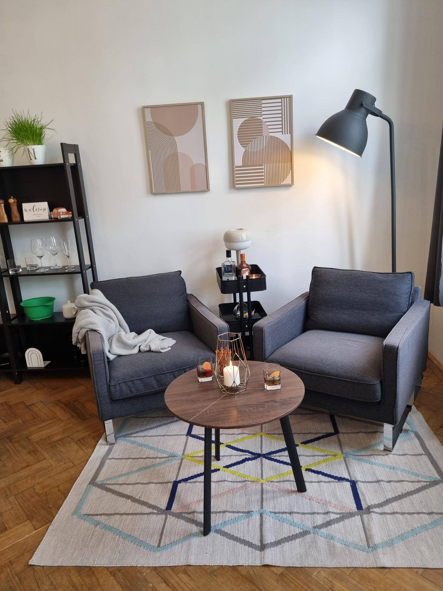 Gemütlicher Wohnbereich mit zwei Sesseln, Couchtisch, Stehlampe und einem Bücherregal.