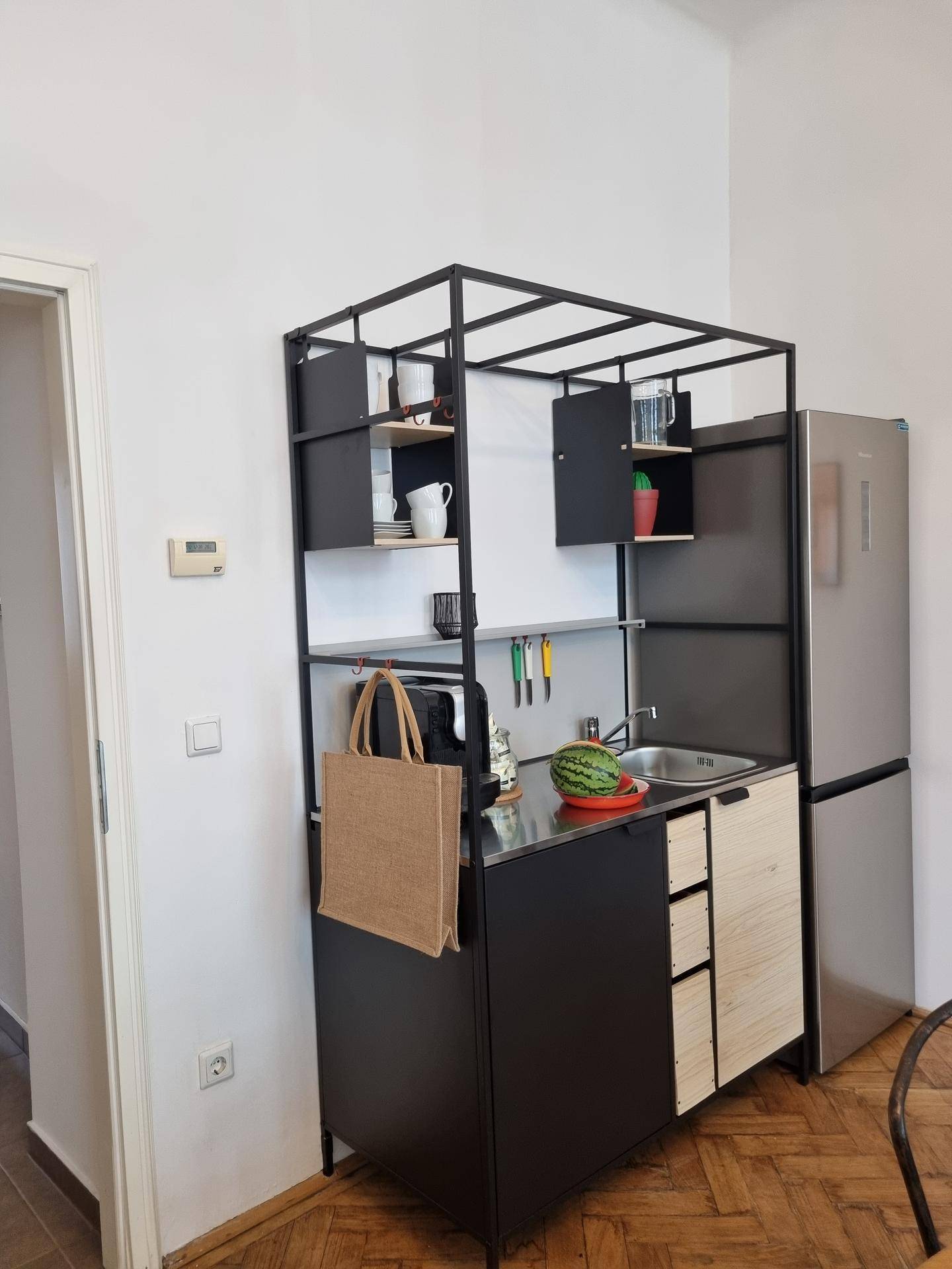 Moderne, kompakte Küchenzeile mit integriertem Kühlschrank und offenen Regalen.