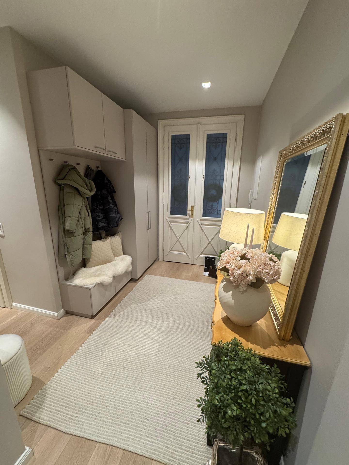 Heller Eingangsbereich mit Garderobe, Spiegel und Holzboden.