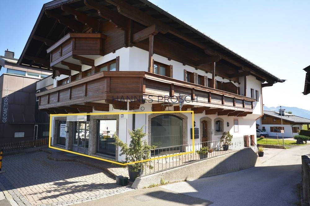 Ansicht eines traditionellen Gebäudes mit Holzbalkonen und einer hervorgehobenen Gewerbefläche im Erdgeschoss.