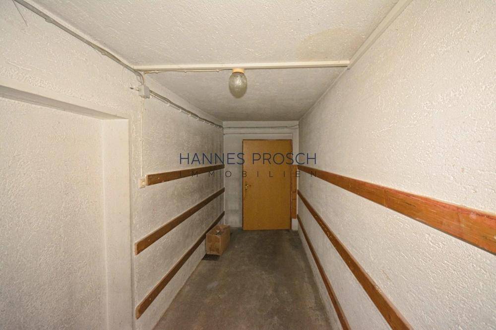 Schmaler Flur mit Holzleisten an den Wänden und einfacher Beleuchtung, in seinem ursprünglichen Zustand.