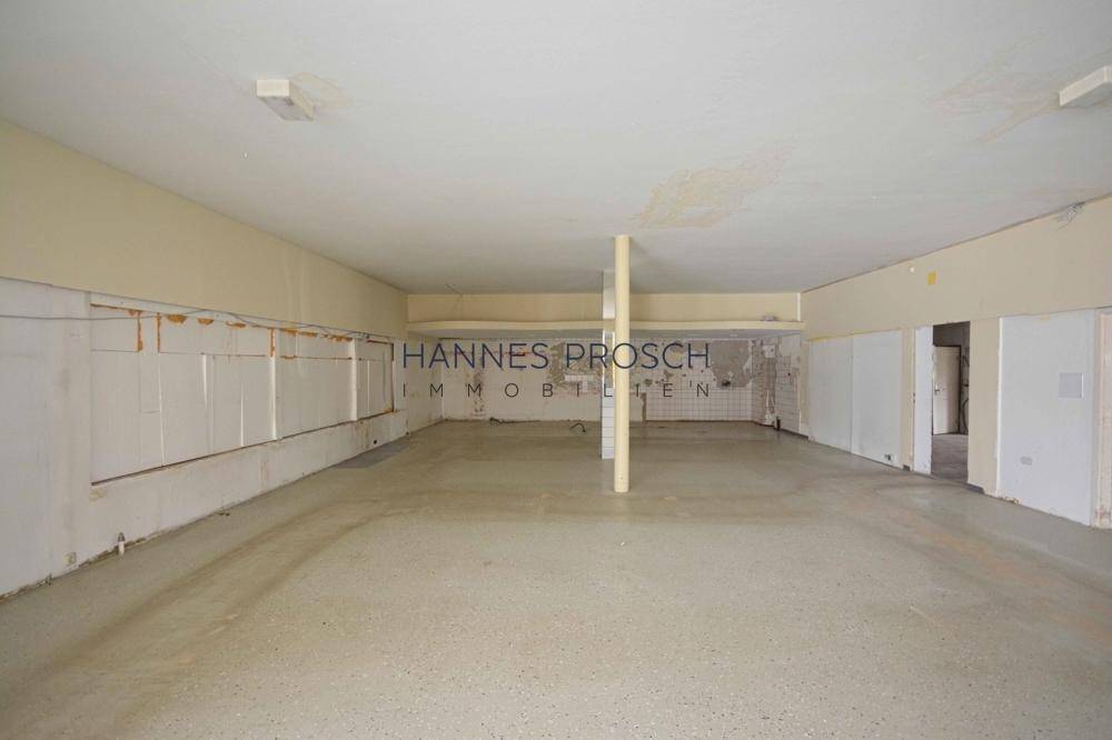 Großer, leerstehender Gewerberaum mit Säulen und vorbereiteten Wänden, ideal für Ladenflächen mit hohen Decken.