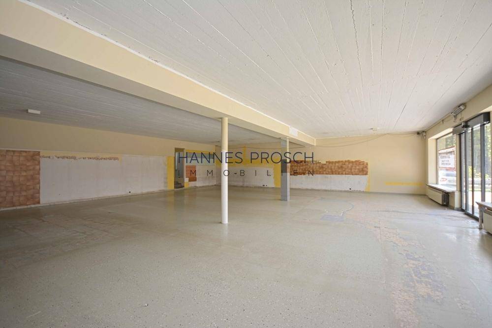 Geräumiger, leerstehender Gewerberaum mit großen Fenstern und Säulen, bereit für den Ausbau und viel Tageslicht.