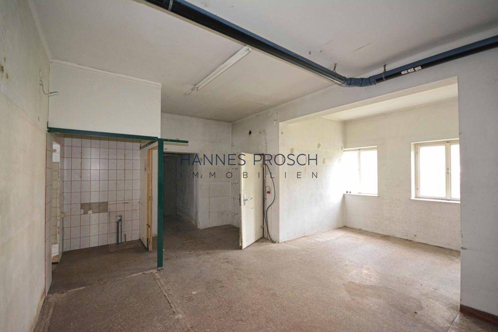 Unfertiger Raum mit Fliesenbereich und sichtbaren Installationen, ideal für Lager oder Sanitäranlagen mit Betonboden.