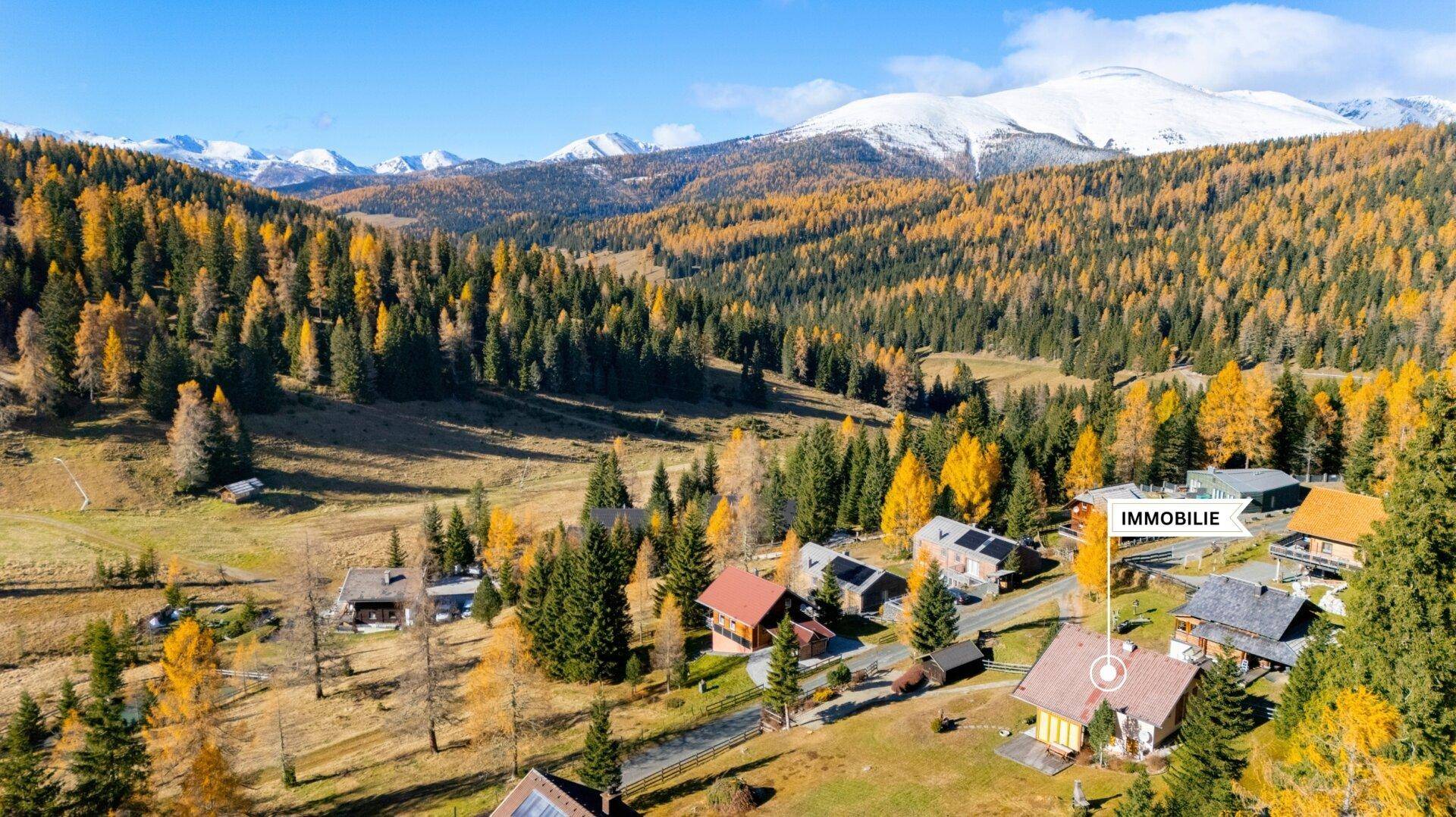 Luftaufnahme der Immobilie in einer malerischen Berglandschaft mit schneebedeckten Gipfeln im Herbst.
