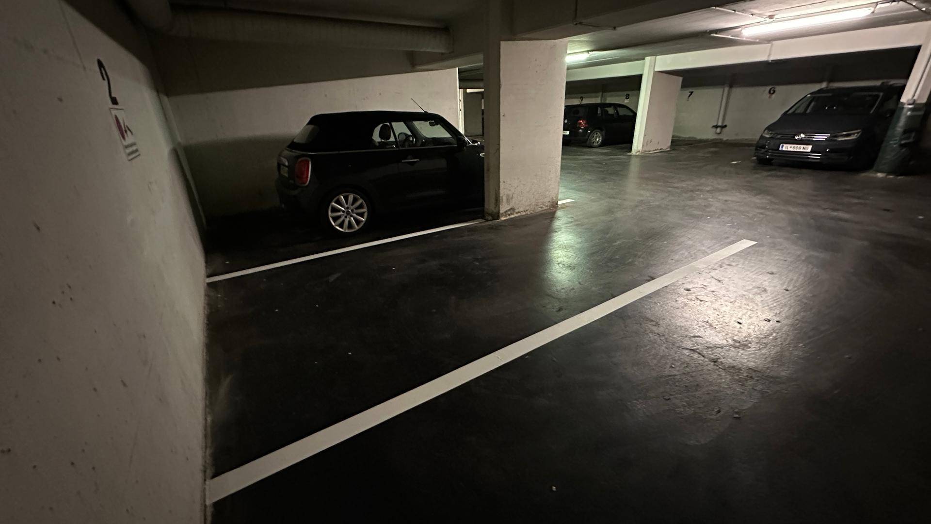 Dunkle Tiefgarage mit einem geparkten schwarzen Mini Cooper und Betonstützen.