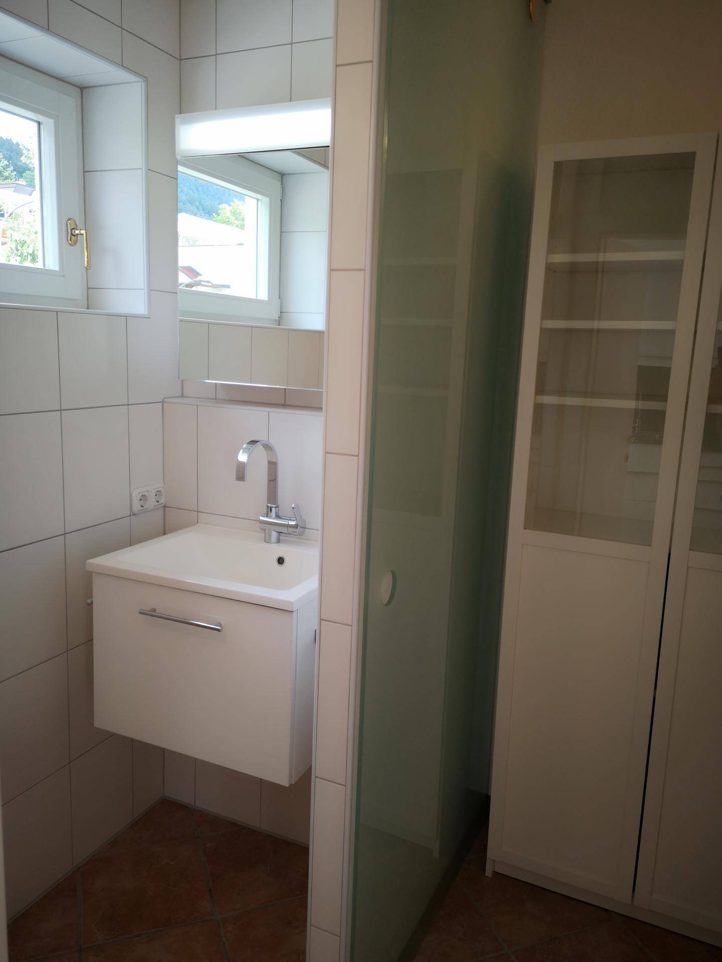 Modernes Badezimmer mit Waschbecken, Spiegelschrank und Duschbereich.