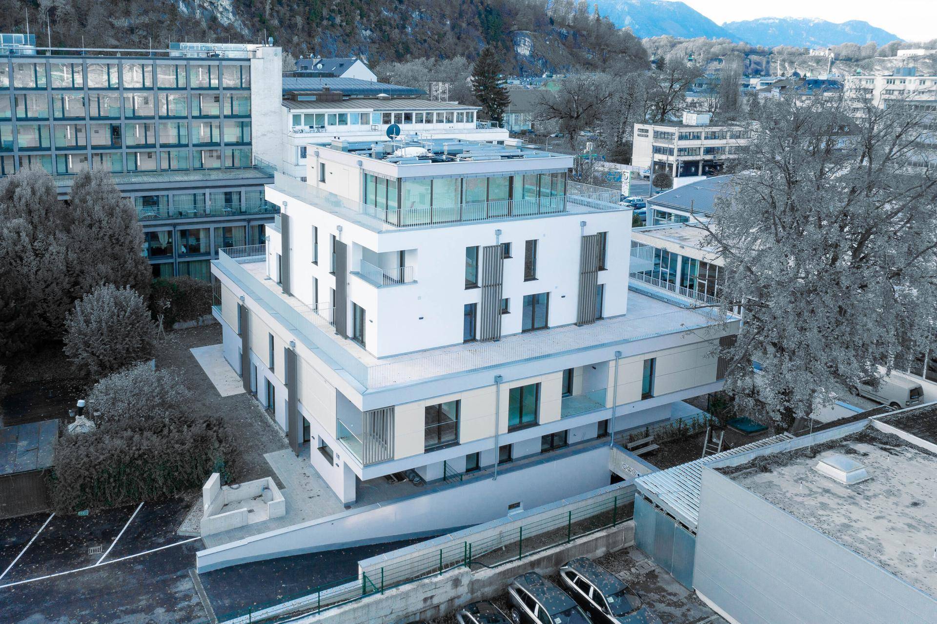 Ansicht der modernen Wohnanlage mit klaren Linien, großen Glasflächen und umliegender Bebauung.