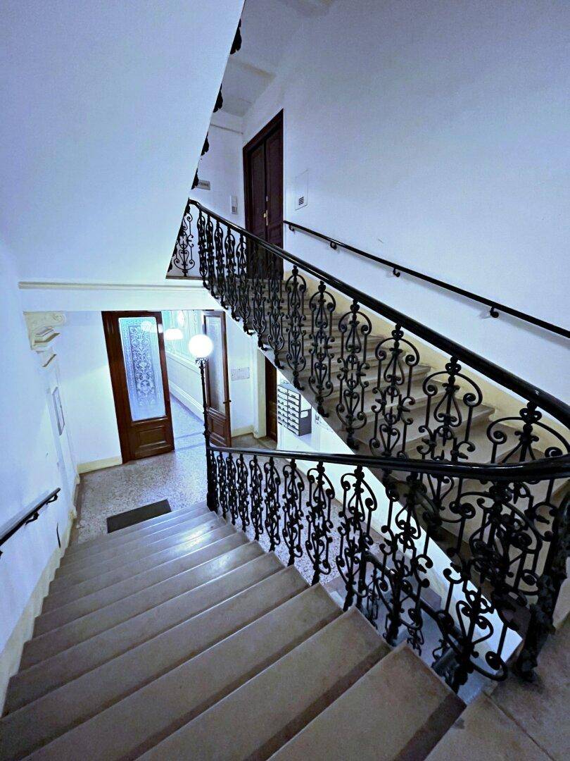 Historisches Treppenhaus mit kunstvollen schmiedeeisernen Geländern und Steinstufen in einem Altbau.