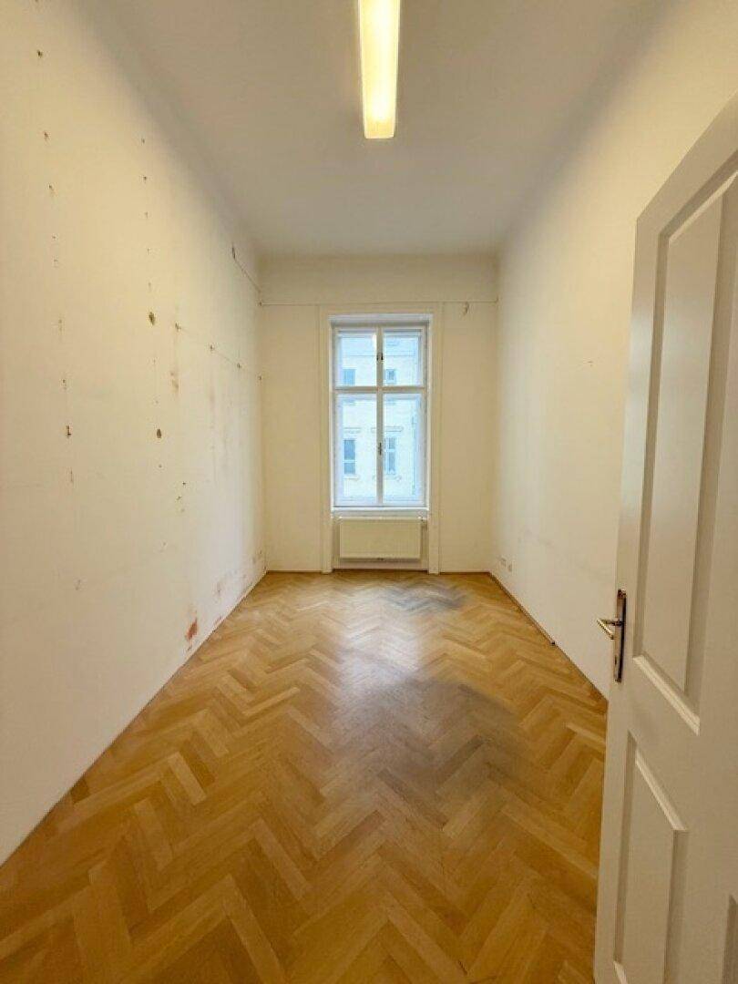 Schmaler Raum mit Fischgrätparkett und einem Fenster, ideal für ein kleines Büro oder Ankleidezimmer.