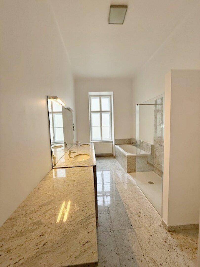 Geräumiges Badezimmer mit Doppelwaschtisch, Badewanne, Dusche und Granitfliesen, sehr hell.